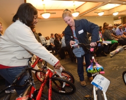 Demetria Hereford helps Tanya Gross select a bike at the annual Books and Bears distribution.  Photo by Nathan Latil/Ole Miss Communications
