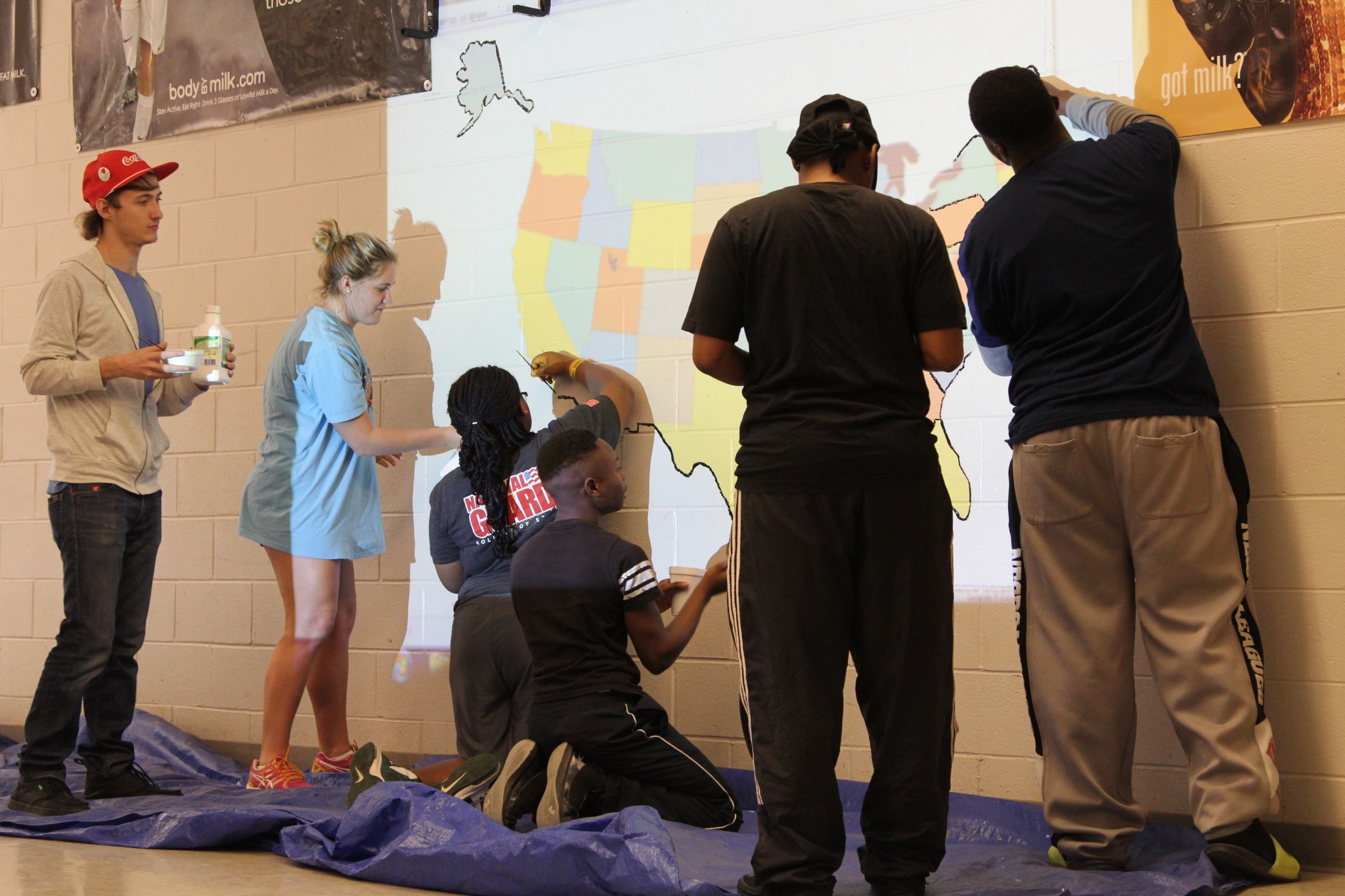 UM students work during their spring break, painting a large map on a wall at a West Tallatchie school. 
