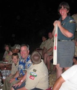 Jim Chambers is 'tapped out' into the Order of the Arrow, a Boy Scout honorary service organization, at Camp Yocona. His wife, Julie, stands behind him with an OA sash, marking him as a candidate.